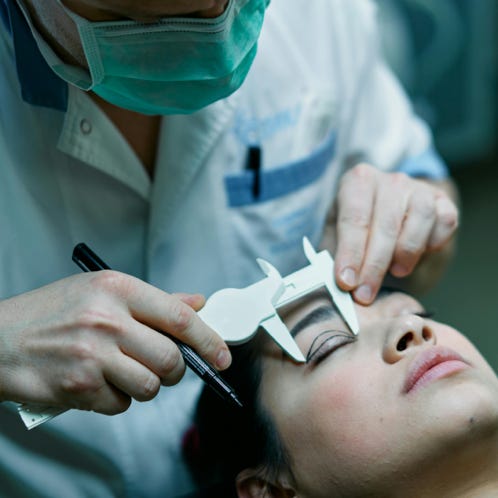 A Cosmetician Measuring a Patient Eyelid